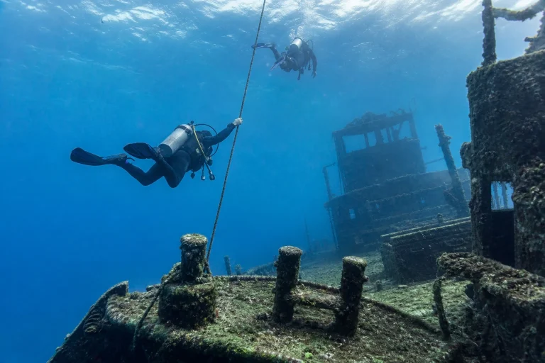 Scuba divers descending toward a large shipwreck off Key West